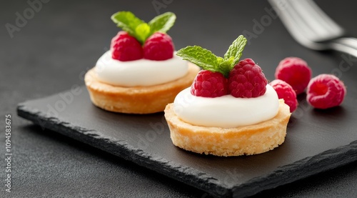 Delicious raspberry tarts on a black serving platter in a modern kitchen setting