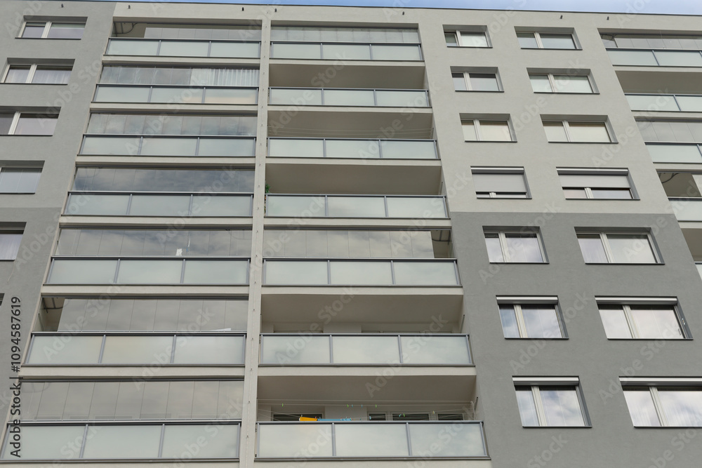 The facade of a modern apartment building features striking design with glass balconies and large windows The facade of a modern apartment building features striking design with glass balconies and large windows