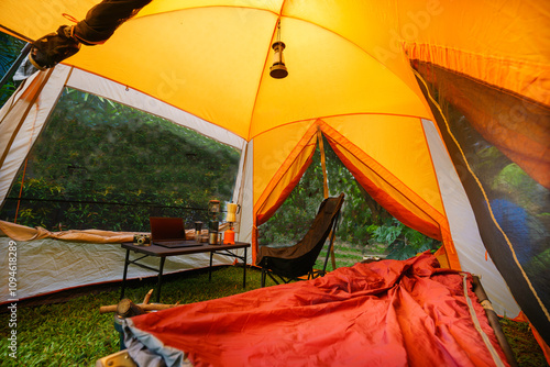 Camping tent: The folding bed inside the tent in the morning, gas lantern and coffee sets, notebooks on a wooden camping table, and outdoor ideas.