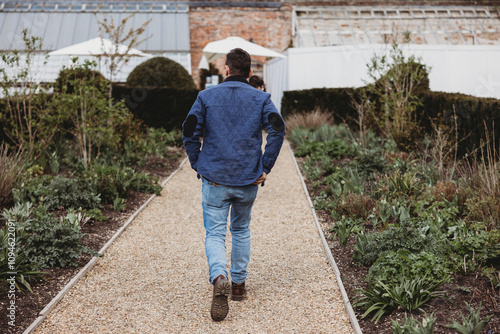 Man in Blue Jacket Walking Down Garden Path, Urban Lifestyle Scene, Rear View