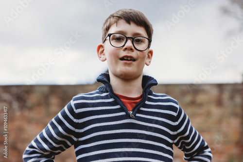 Smiling boy with glasses outdoors in a striped jumper