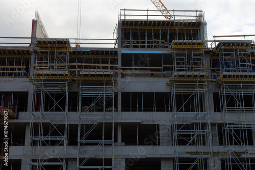 Wallpaper Mural A construction scene illustrates scaffolding prominently situated with a large building seen in the distance Torontodigital.ca