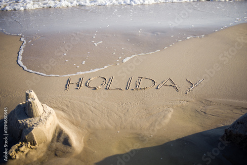 Inscription in the sand. Holiday inscription on the beach witg sand castle photo