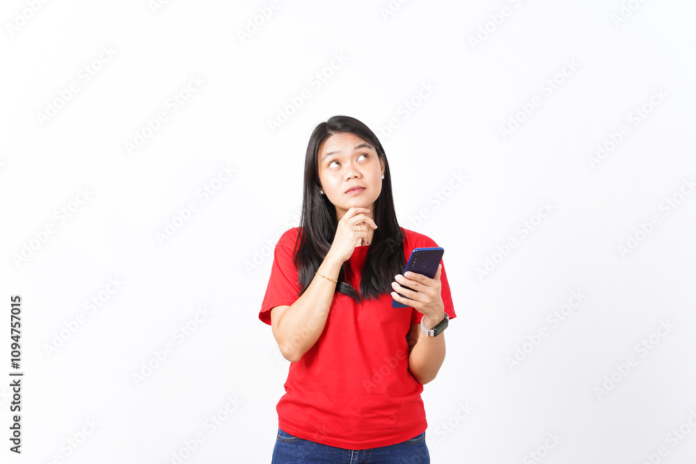 beautiful Asian woman, deep in thought, looks upward while holding a smartphone, set against a white background beautiful Asian woman, deep in thought, looks upward while holding a smartphone, set against a white background