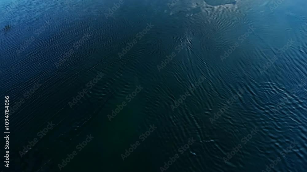 Aerial view of dark blue water with gentle waves and reflections of clouds. Aerial view of dark blue water with gentle waves and reflections of clouds.