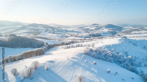 Aerial winter background with snow-covered hills and valleys under a pale blue sky