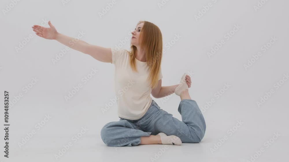 Woman practicing the mermaid yoga pose in casual clothes against a clean white background, showcasing flexibility and balance Woman practicing the mermaid yoga pose in casual clothes against a clean white background, showcasing flexibility and balance
