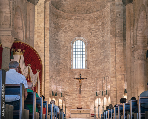 View from the apse of the transept of the cathedral of Trani, some faithful sit in prayer on the benches. The great height of the cathedral is highlighted. Trani - ITALY