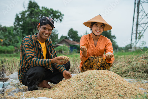 Two dedicated farmers proudly showcasing their bountiful rice harvest in a beautiful, fertile field photo