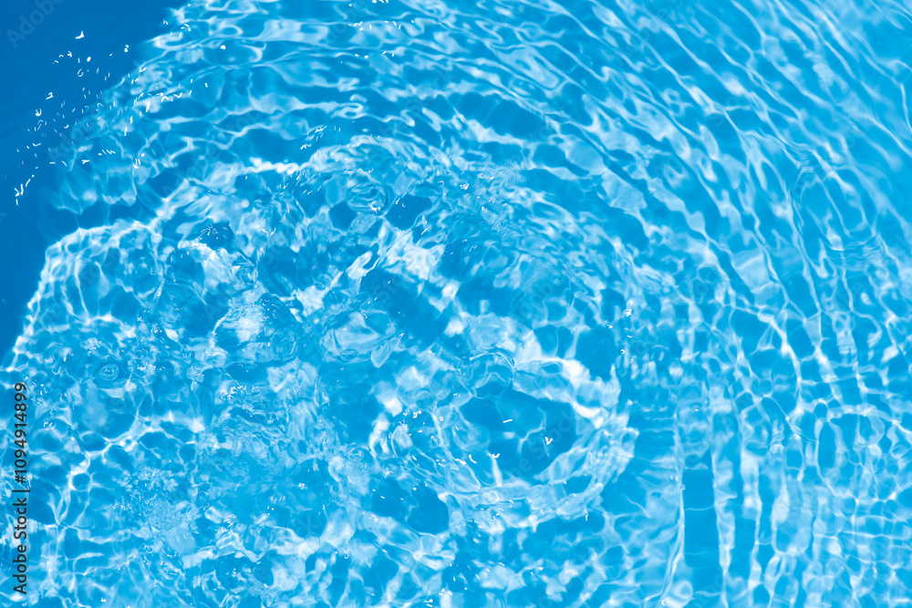Fototapeta premium Blue water with ripples on the surface. Defocus blurred transparent blue colored clear calm water surface texture with splashes and bubbles. Water waves with shining pattern texture background.