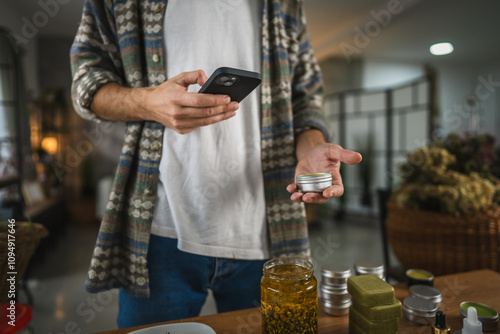 adult man take a photo of natural salve with cellphone at workshop photo