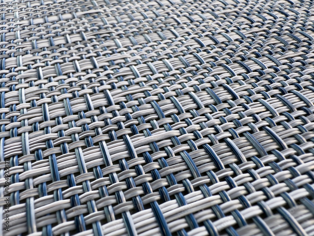 Closeup of a modern woven synthetic place mat on a restaurant table outdoors, for background or texture with motifs of design and manufacture, consistency, interconnectedness. Shallow depth of field. Closeup of a modern woven synthetic place mat on a restaurant table outdoors, for background or texture with motifs of design and manufacture, consistency, interconnectedness. Shallow depth of field.