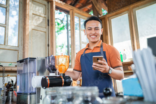 coffee shop waiter standing holding phone with smiling face