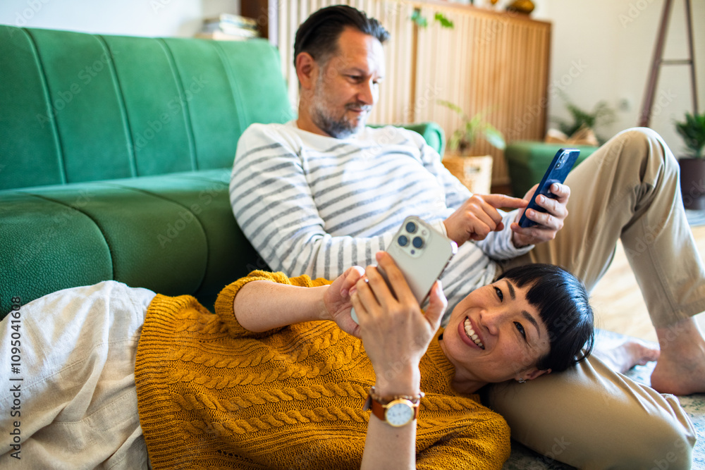 Obraz premium Happy couple relaxing on the couch and sharing a moment while looking at a smartphone