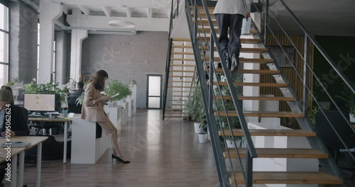 Businesspeople diverse group working in office walking talking using computers at desks. Busy workplace and professional occupation concept.