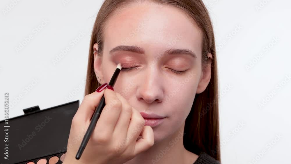 Portrait of a beautiful woman with fresh nude make-up, thick eyebrows and with clean skin. Makeup artist does eye makeup in a beauty salon. Cosmetology and Makeup concept. Portrait of a beautiful woman with fresh nude make-up, thick eyebrows and with clean skin. Makeup artist does eye makeup in a beauty salon. Cosmetology and Makeup concept.