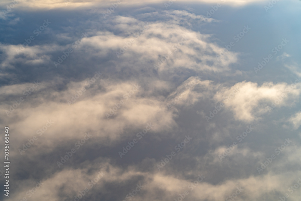 Obraz premium View of soft clouds under a vast sky during daytime flight above the landscape, capturing a serene atmosphere and natural beauty