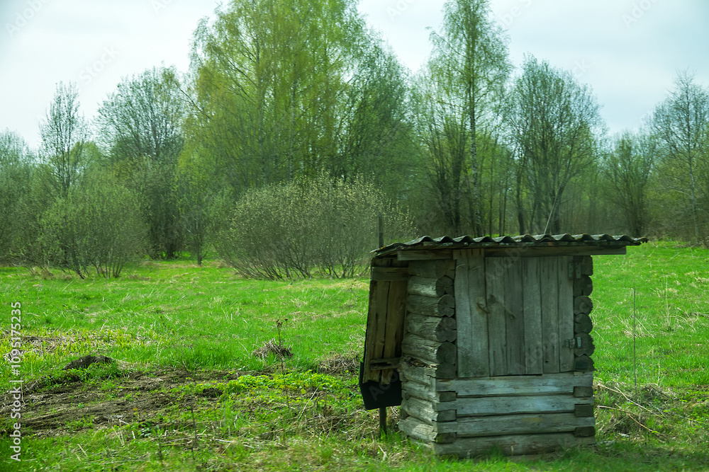 A wooden barn on the edge of a field and forest A wooden barn on the edge of a field and forest