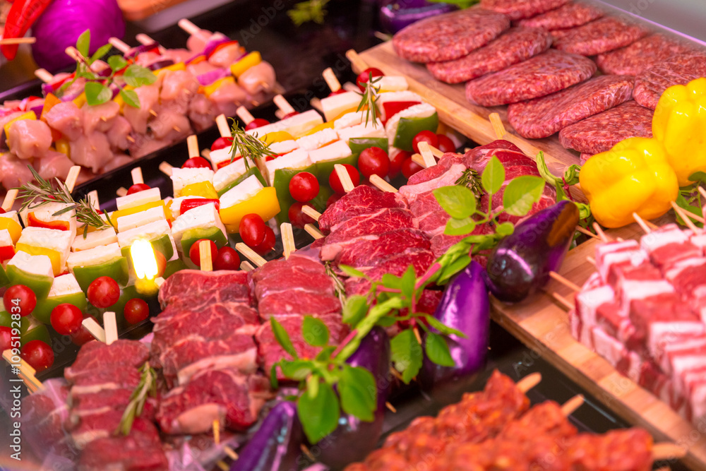 Fototapeta premium Row beef burger cutlets and lamb meat for grilled raw meat products seasoned with mixed peppers and rosemery on skewers. Diverse raw meat products for sale.