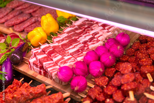 Grilled raw pork meat products seasoned with mixed peppers and rosemery on skewers. Diverse raw meat products for sale. photo