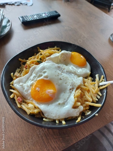 A close-up of a plate of pasta topped with two perfectly cooked fried eggs. The dish looks simple, yet satisfying.