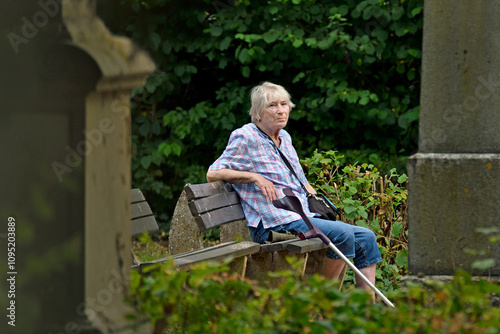 seniorin sitzt auf einer friedhofsbank