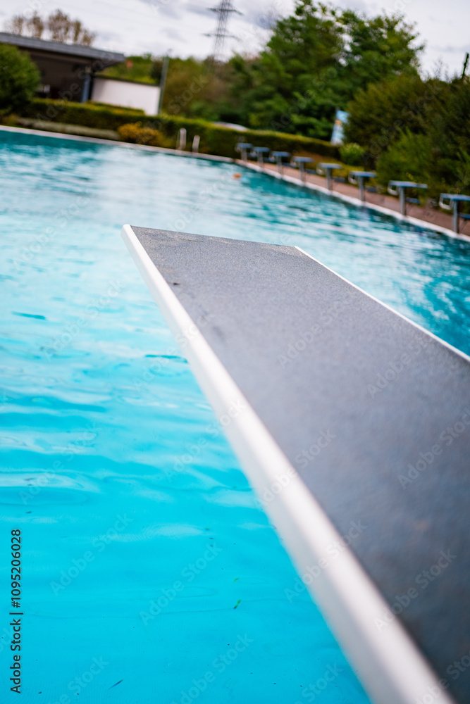 Fototapeta premium Inviting Diving Board Overlooking a Empty Tranquil Blue Outdoor Swimming Pool