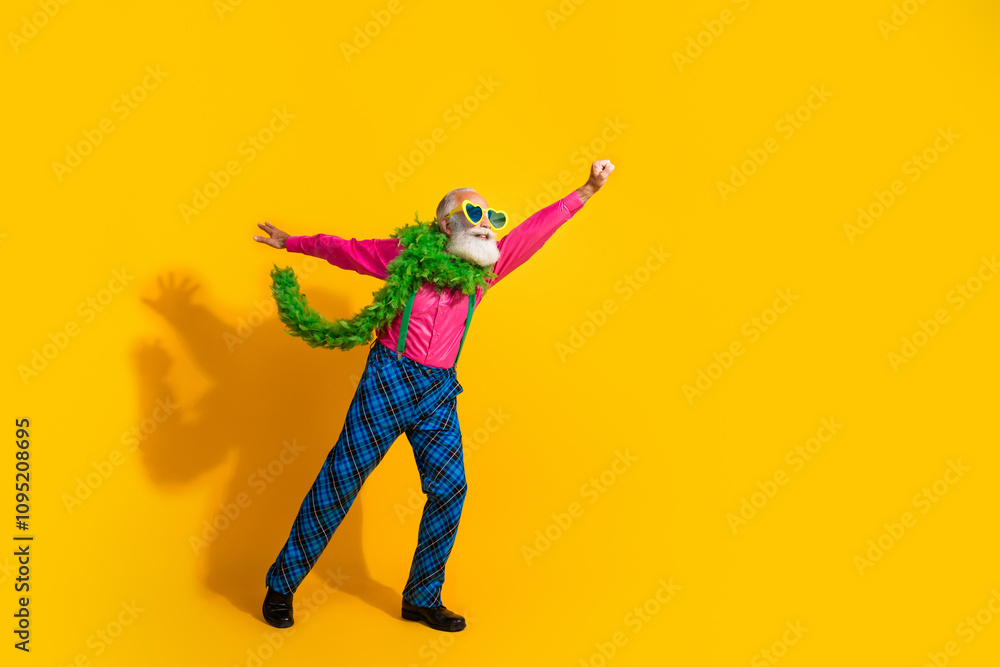Full length photo of senior male flying showman raise fist boa wear pink shirt plaid pants suspenders fancy outfit on yellow background Full length photo of senior male flying showman raise fist boa wear pink shirt plaid pants suspenders fancy outfit on yellow background