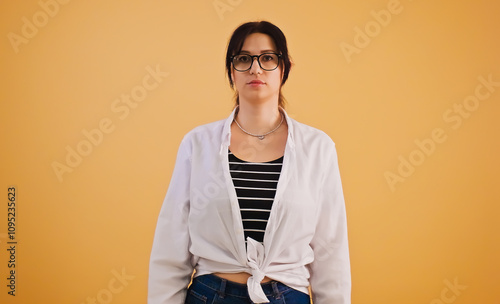 Confident young woman stands calm and straight on orange background