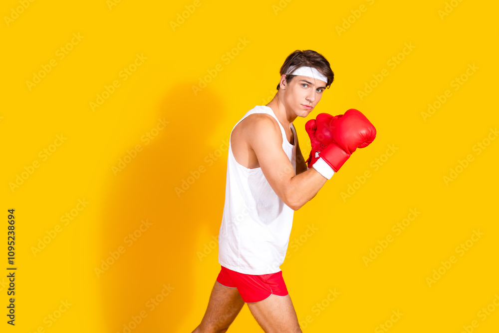 Young athletic man in boxing stance with red gloves on vibrant yellow background ready for a workout Young athletic man in boxing stance with red gloves on vibrant yellow background ready for a workout