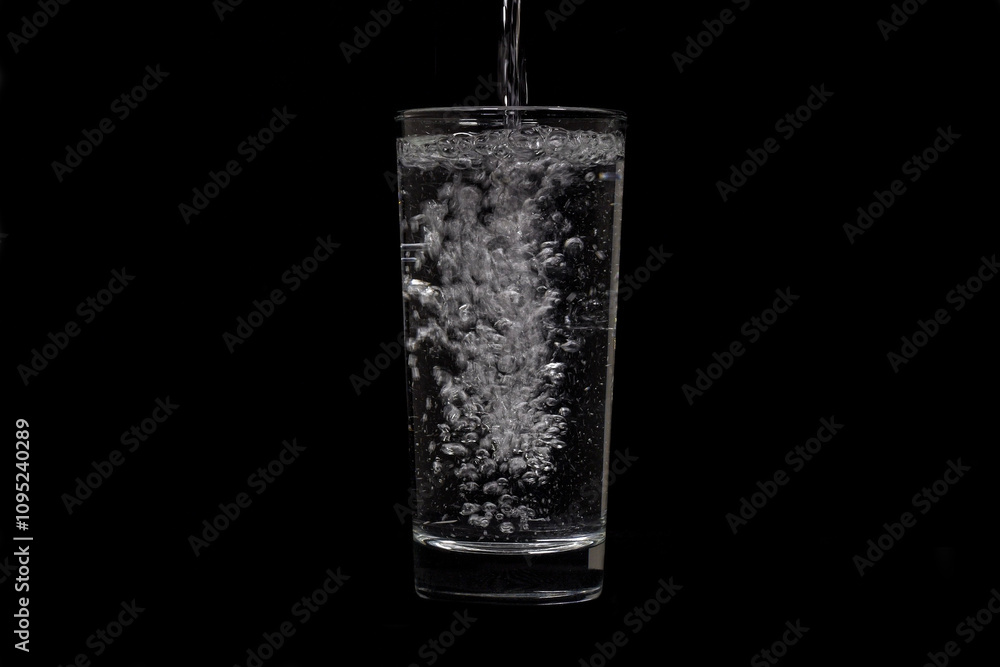 Image of water pouring into glass on black background. Image of water pouring into glass on black background.