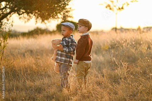 boys playing in the garden with a teddy bear and eating apples from the trees