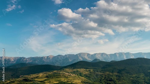 Landscape with fast movement of clouds in the sky, sunlight and shadows on the ground.Time Lapse. Zoom Out. View of the small village of Toloriu in the Pyrenees mountains of Catalonia, Spain. photo