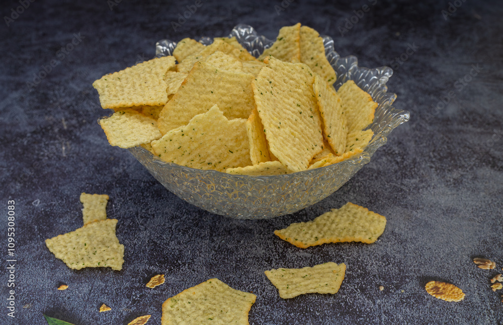 Crispy wavy potato chips or crisps bowl isolated on dark background. Party food. Salty snack