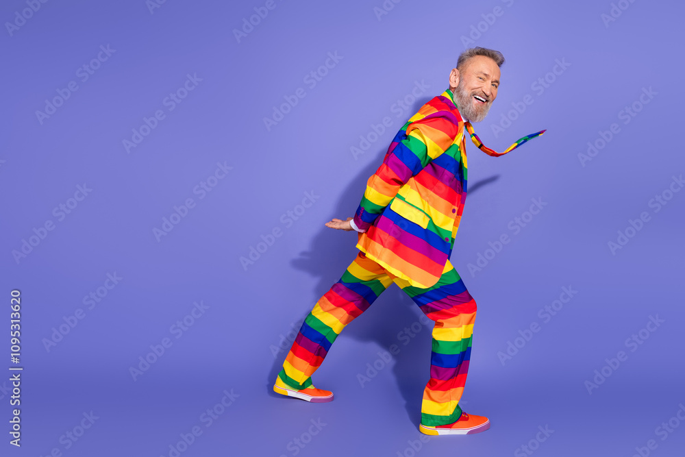 Elderly man in vibrant rainbow suit celebrating individuality against purple background Elderly man in vibrant rainbow suit celebrating individuality against purple background