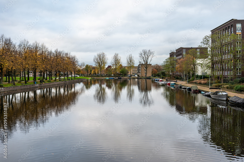 Houses and autumn color trees reflecting in the Admiral's canal in Amsterdam, The Netherlands Houses and autumn color trees reflecting in the Admiral's canal in Amsterdam, The Netherlands