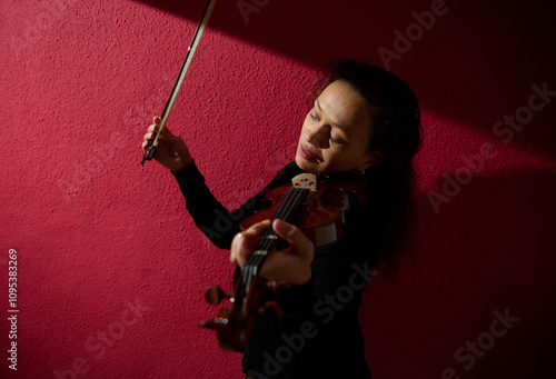 Violinist playing passionately against a textured red background photo