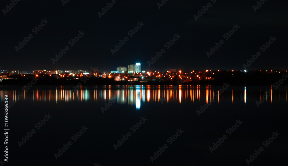 The lights of the city of Constanta - Romania reflected in the water of Lake Siutghiol. Night view of the city lights reflected in the water The lights of the city of Constanta - Romania reflected in the water of Lake Siutghiol. Night view of the city lights reflected in the water
