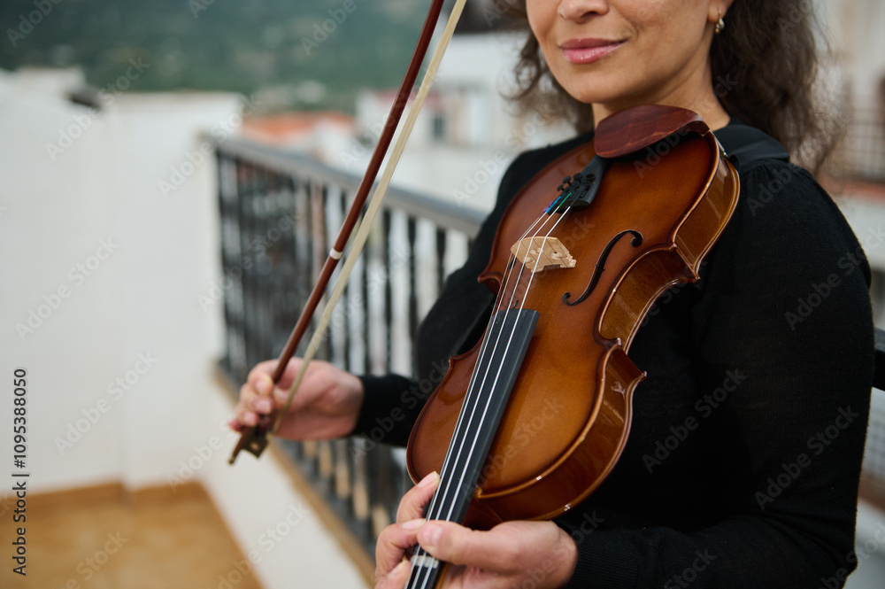 Woman practicing violin on a balcony with scenic view Woman practicing violin on a balcony with scenic view