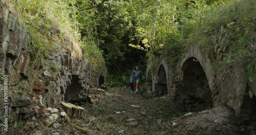 Three friends run past the ruins of a historic building. A sunny summer day. photo