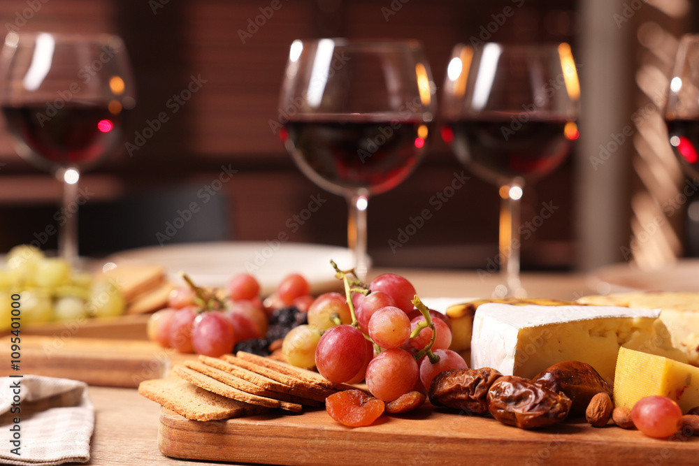 Glasses of red wine and different snacks on wooden table, selective focus Glasses of red wine and different snacks on wooden table, selective focus