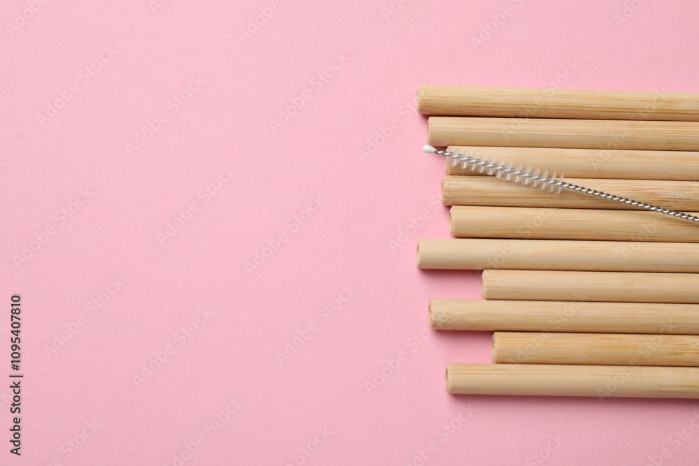 Bamboo drinking straws and cleaning brush on pink background, top view. Space for text Bamboo drinking straws and cleaning brush on pink background, top view. Space for text