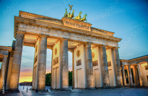 Built in 1873, the sandstone Brandenburg Gate, the symbol of German unity, has its fluted, Doric columns, lighted for the upcoming evening at blue hour in Berlin, Germany on a summer evening. photo