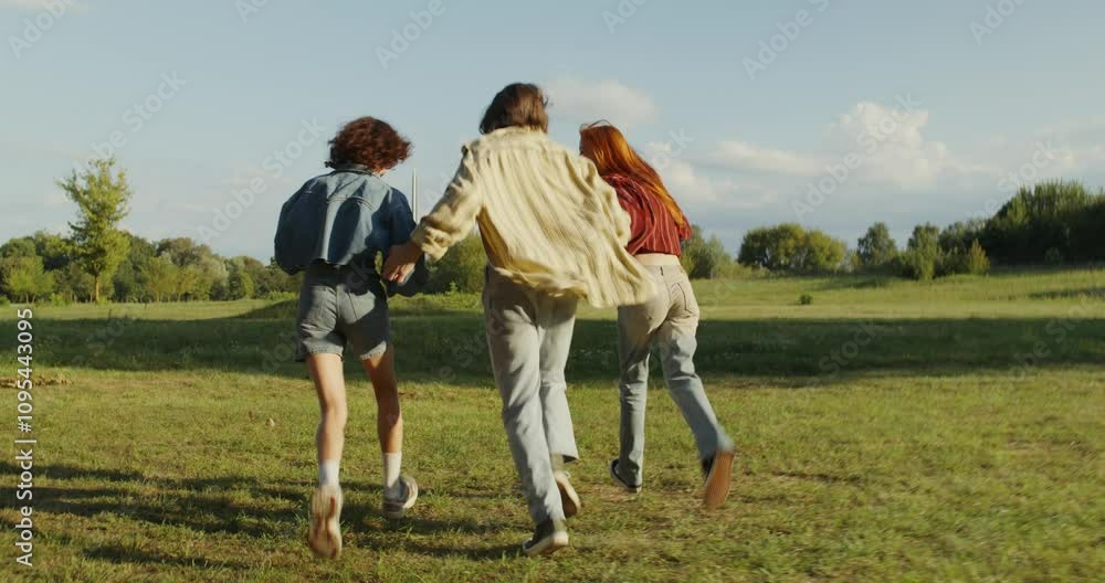 Three friends are smiling and running around the green lawn in the park. A sunny summer day. Carefree youth Three friends are smiling and running around the green lawn in the park. A sunny summer day. Carefree youth