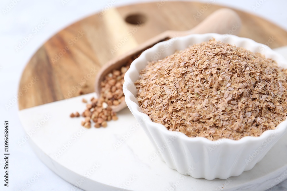 Buckwheat bran in bowl on white table, closeup. Space for text Buckwheat bran in bowl on white table, closeup. Space for text