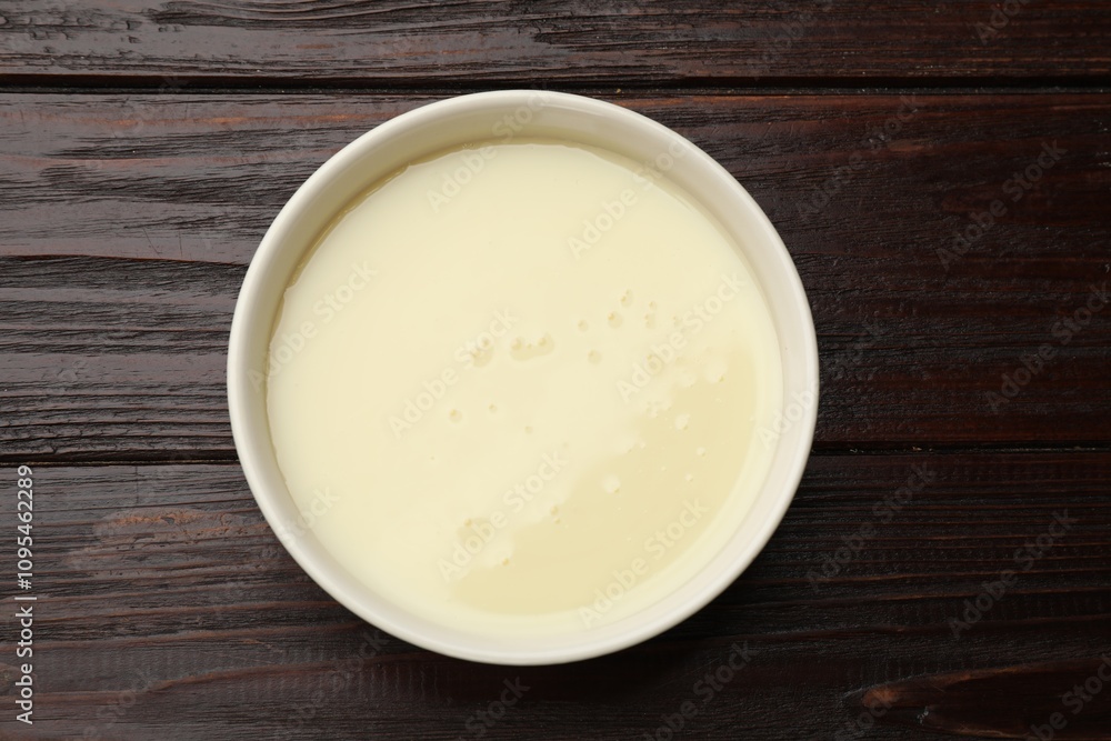 Condensed milk in bowl on wooden table, top view Condensed milk in bowl on wooden table, top view