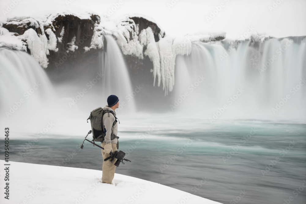 Obraz premium Cameraman standing next to beautiful iceland waterfall and pool