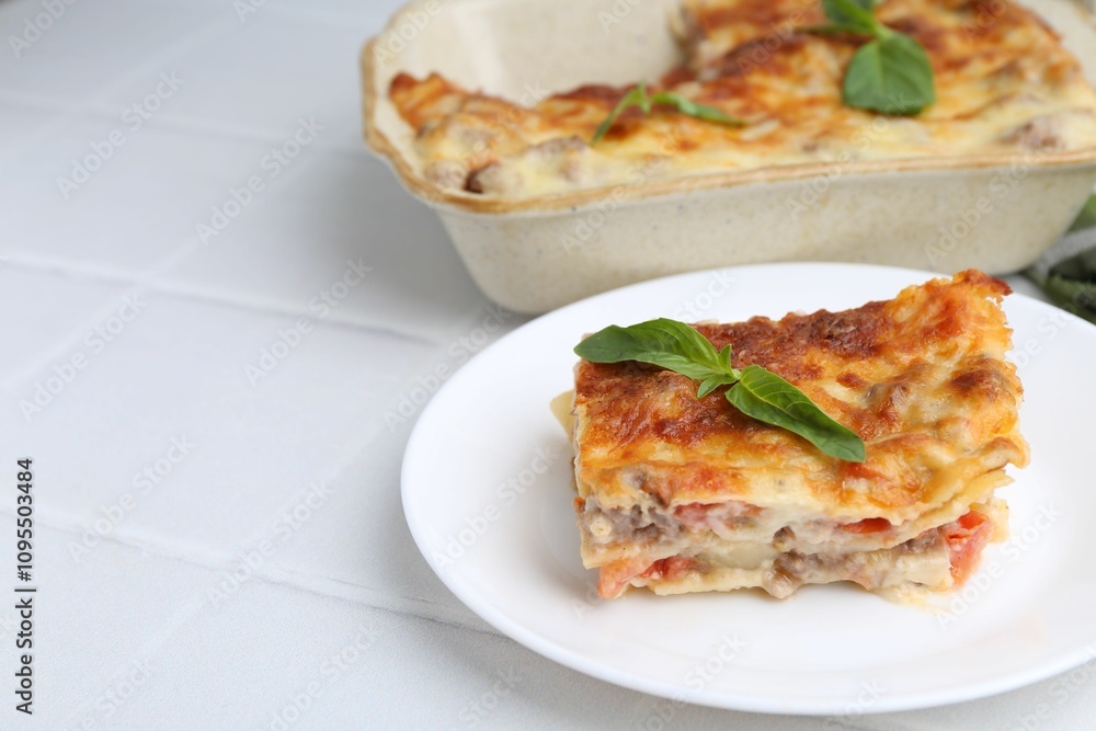 Piece of delicious cooked lasagna with basil on white tiled table, closeup. Space for text Piece of delicious cooked lasagna with basil on white tiled table, closeup. Space for text