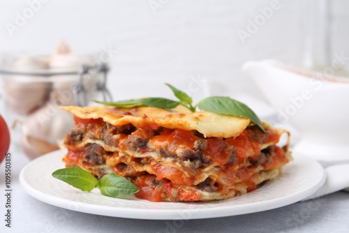 Delicious cooked lasagna with basil on light table, closeup