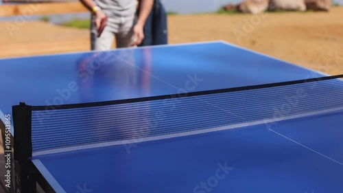 Ping-pong game, group of friends playing ping pong in a park,  play table tennis, family game in the backyard, colleagues teammates during competition at work, racket and ball on a blue tennis table